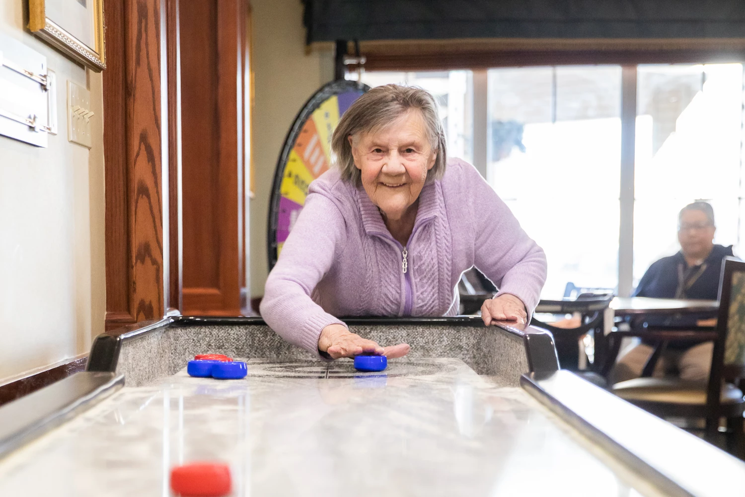 Senior female pushing a blue disk on a shuffle board