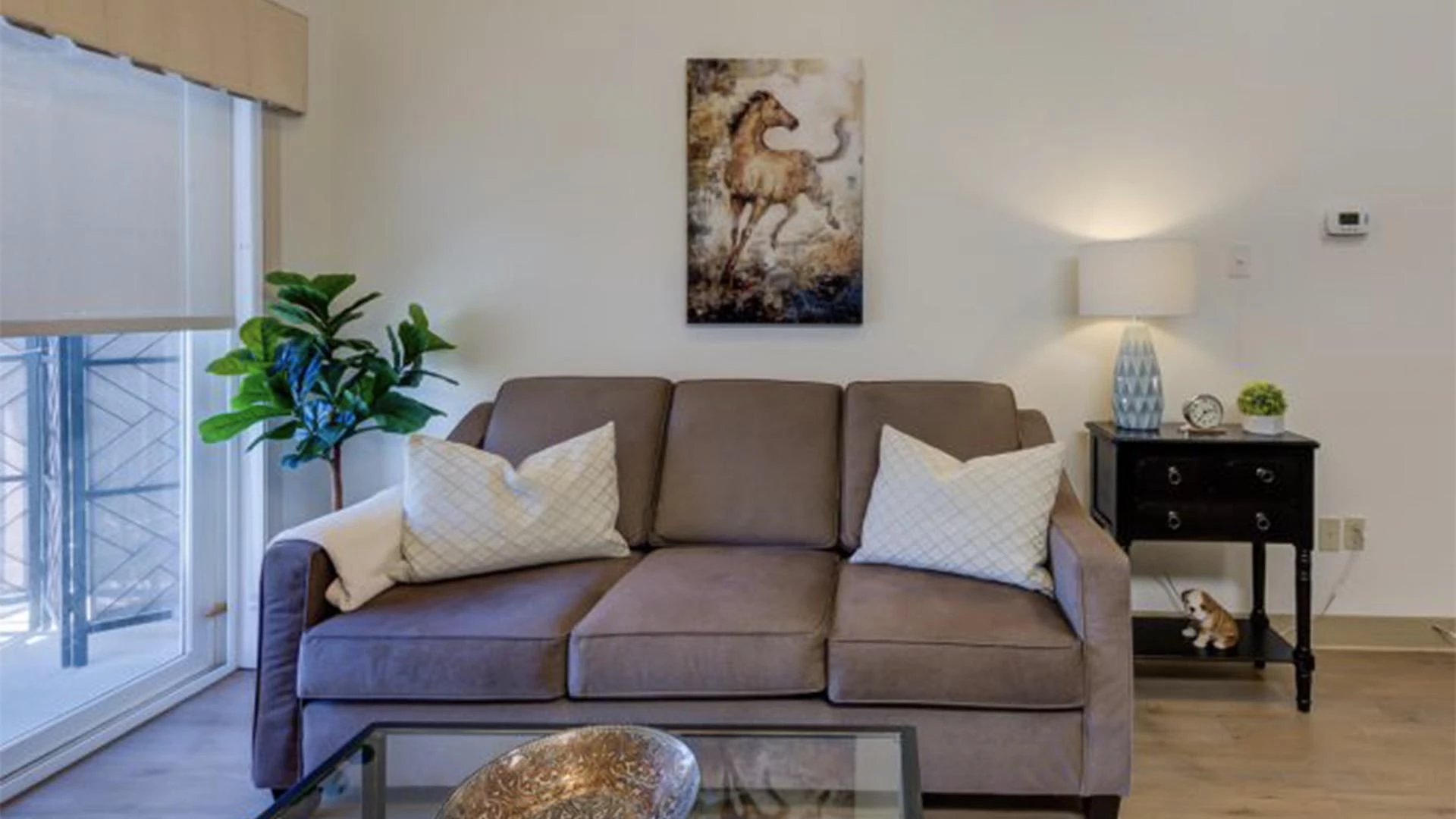 A brown couch with a side table and horse wall painting in a Rutherford Heights senior apartments