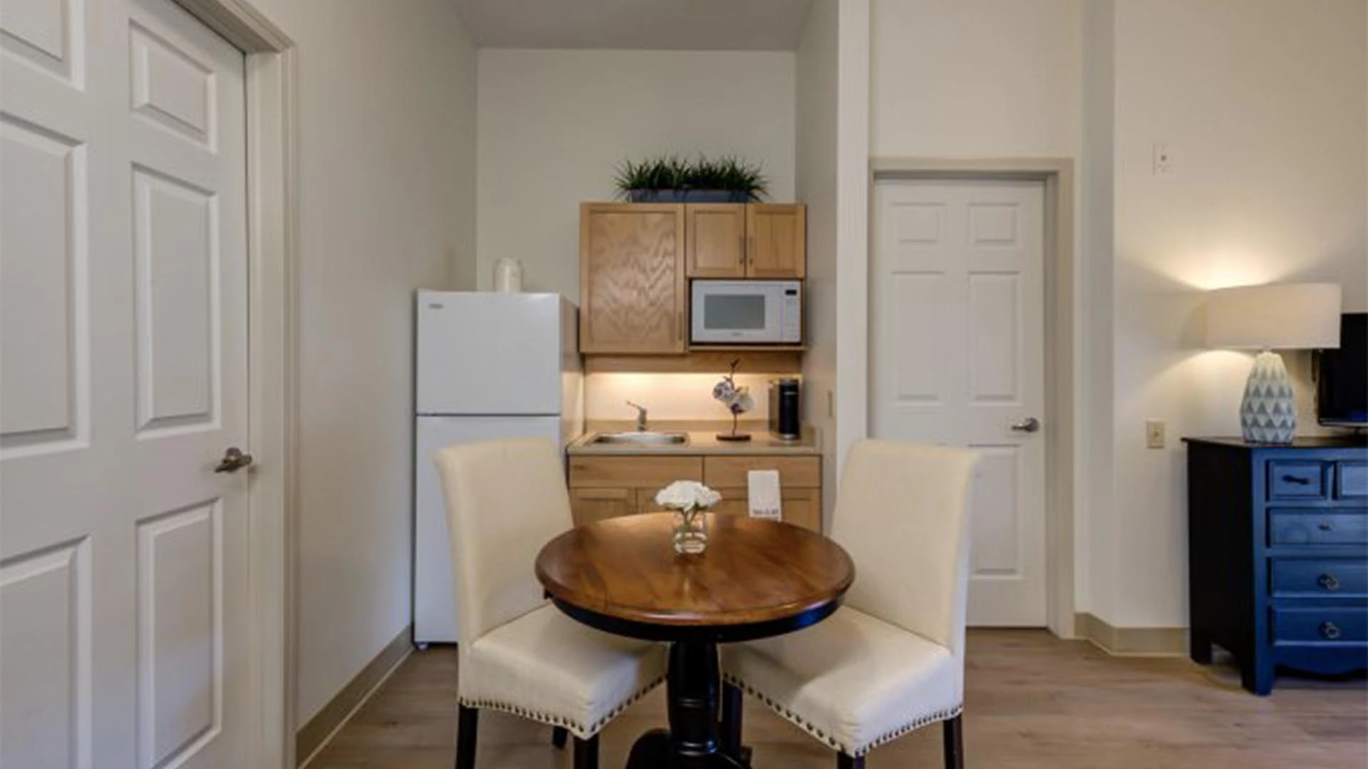 A Rutherford Heights senior apartments  kitchenette with fridge, sink, microwave, and table with chairs